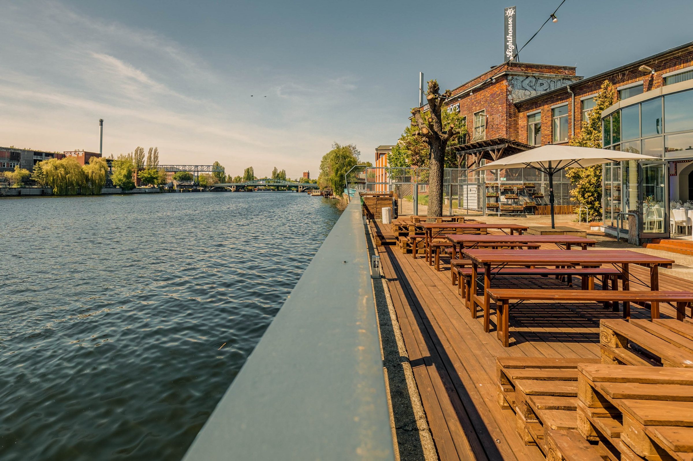 Holzterrasse des Lighthouse direkt an der Spree mit Bierbänken und Palettenmöbeln