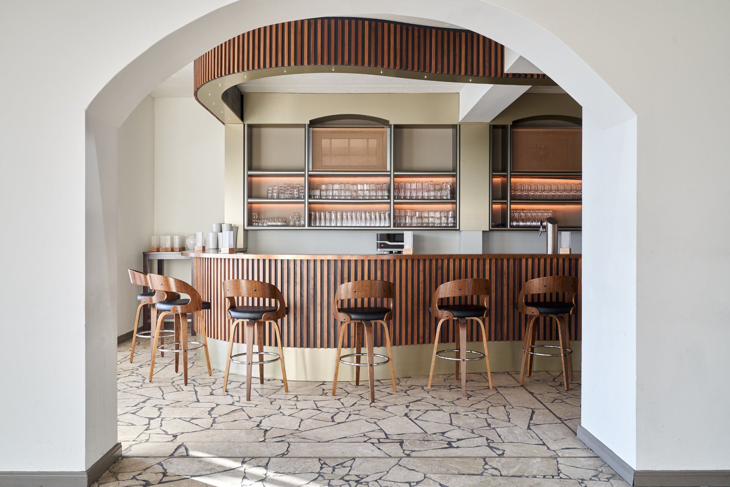 Bar der Panoramalounge mit Holzlamellen, Barhockern und beleuchteten Regalen