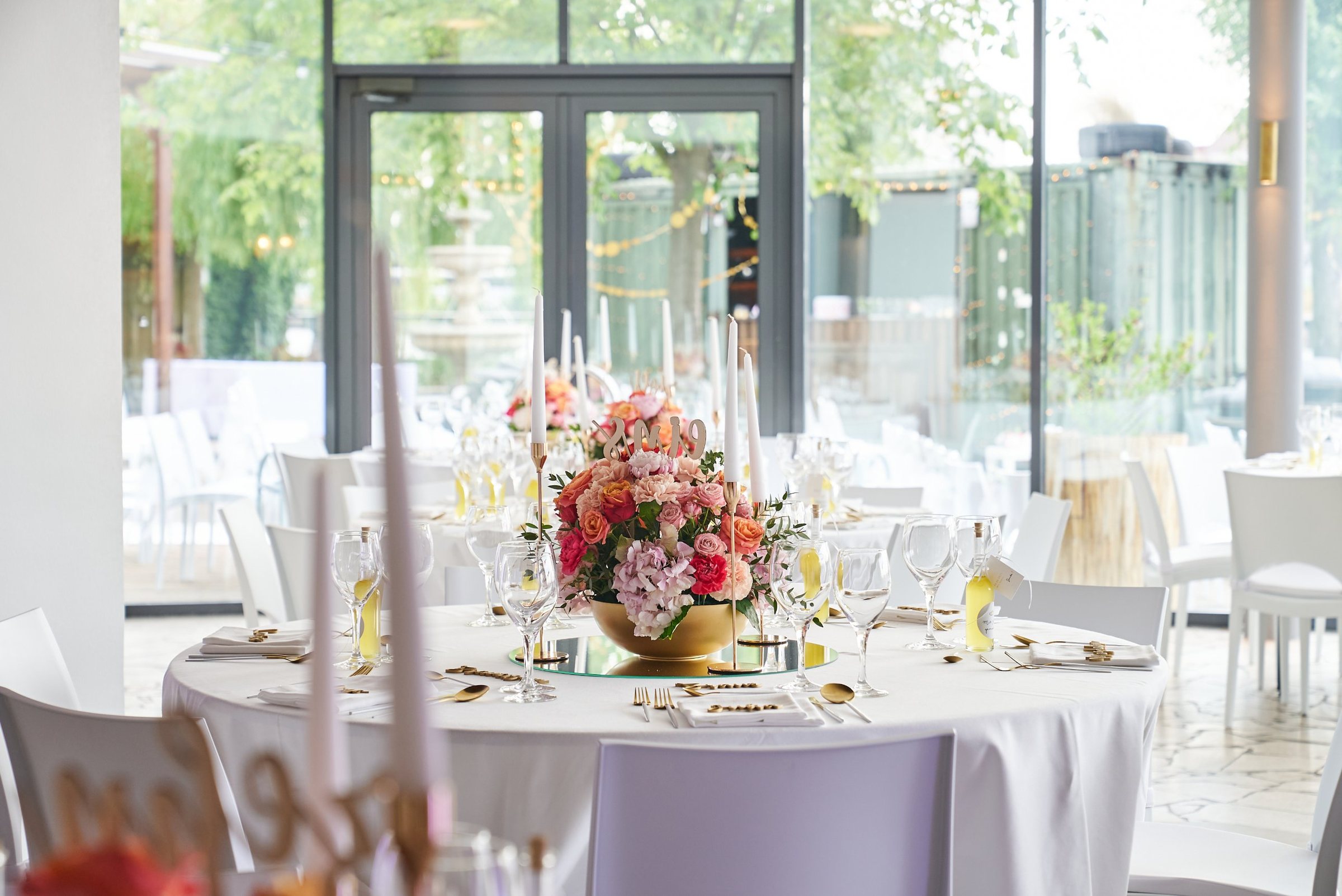 Festlich gedeckter Hochzeitstisch mit Blumen, goldenem Besteck und Kerzen in der Panoramalounge