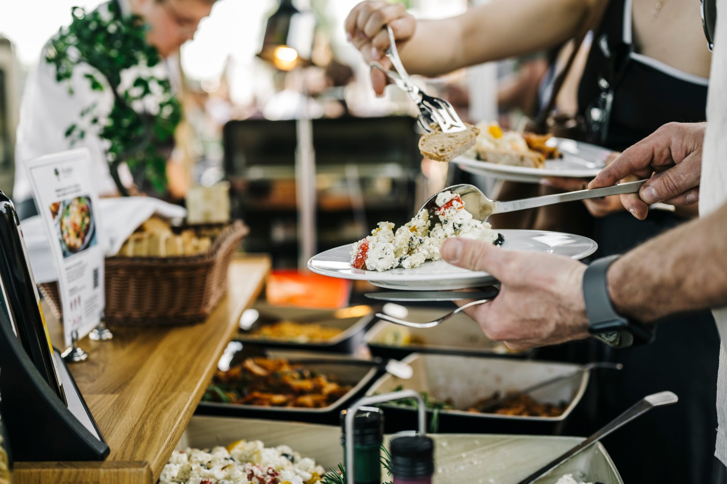 Gäste bedienen sich am Buffet mit Salaten, Brot und warmen Speisen