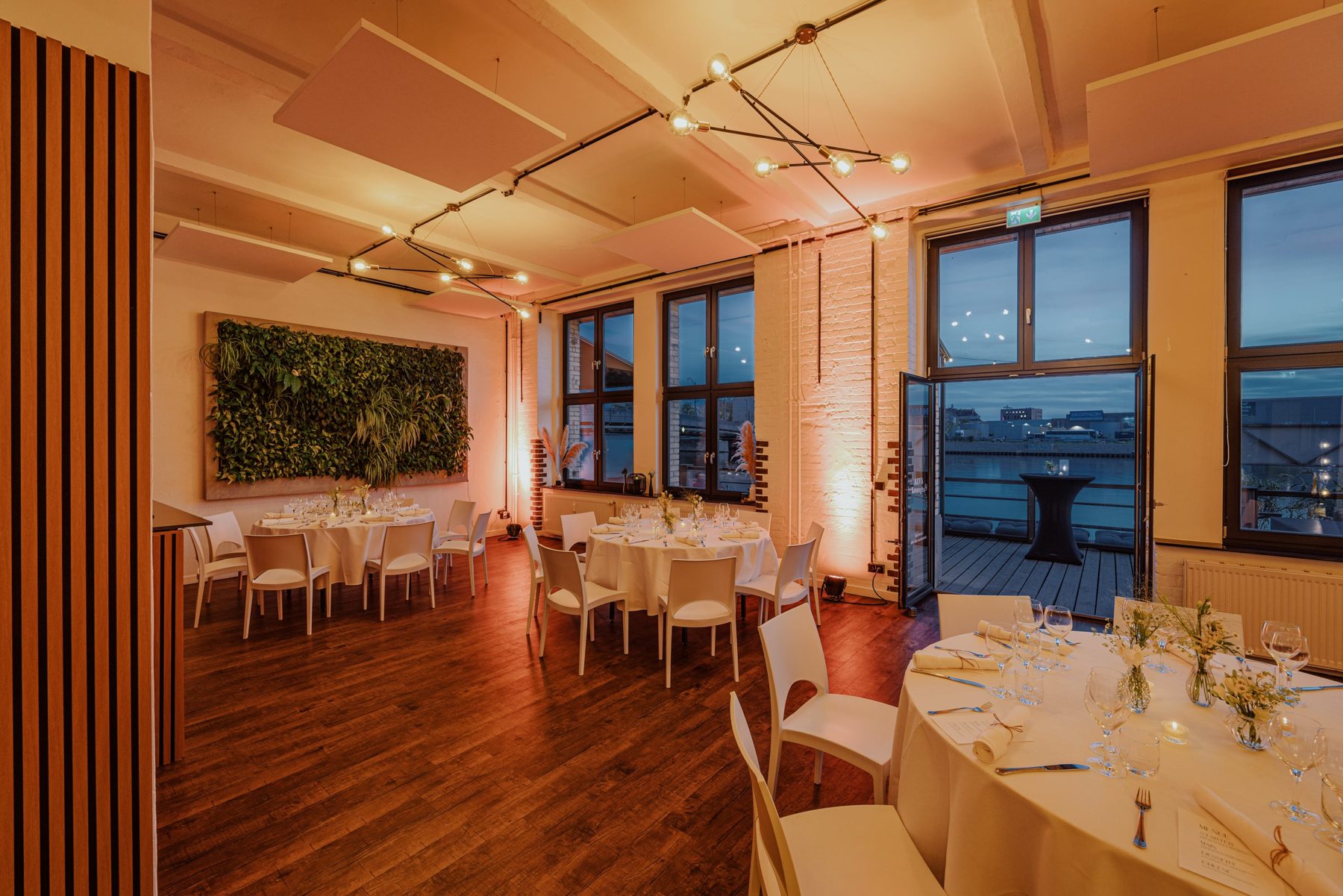 Abendlich beleuchteter Saal mit Holzboden und runden Tischen: ALVA Lounge in der WHITE Spreelounge